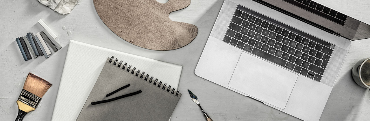 Skrivbord ovanfrån med en dator och block och målartillbehör